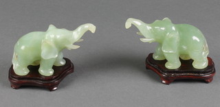 A pair of green hardstone figures of standing elephants on hardwood bases 4" contained in plush cases