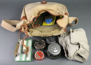 An Allcocks canvas and leather tackle bag containing fly jacket, reels etc 