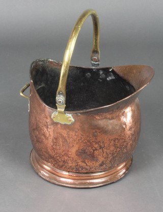 A copper helmet shaped coal scuttle with brass swing handle 