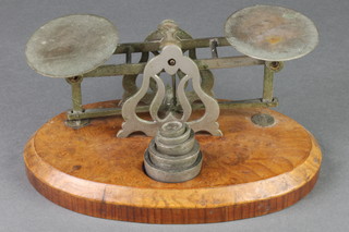 A pair of oval metal letter scales raised on oval figured walnut base 