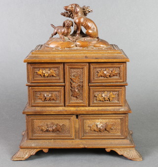 A Swiss carved wooden jewellery box fitted 4 compartments, having a hinged lid with the finial in the form of 2 seated dogs by arbour, raised on bracket feet 10"h x 9 1/2"w x 5 1/2"d 