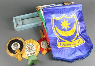 A box containing various football rosettes, banners and a rattle