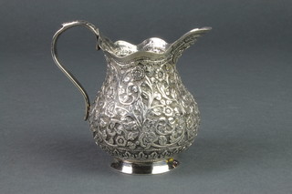 A Persian silver cream jug with repousse scroll and floral decoration 110 grams
