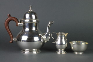 A silver 3 piece matched tea set comprising teapot with fruit wood handle, a baluster cream jug and sugar bowl, Birmingham 1928 and 1931, 912 grams gross