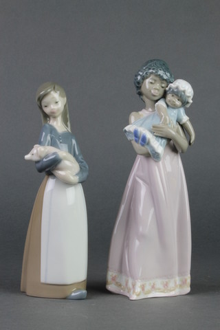 A Lladro figure of a young girl holding a piglet. 1011 6 1/2" and a lady holding a child. 5600 7 1/2" 