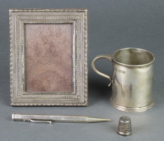 A silver christening mug, London 1915, a thimble, photograph frame and pencil 