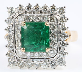 An 18ct yellow gold emerald and diamond square shaped dress ring, the centre stone approx. 2.5ct surrounded by 2 tiers of brilliant cut diamonds, approx. 1.0ct, size N
