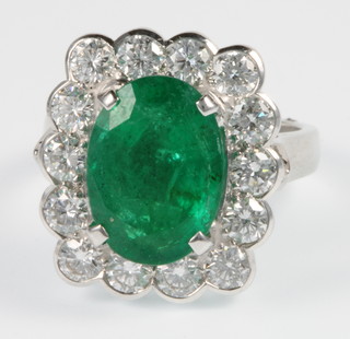 An 18ct white gold emerald and diamond cluster ring, the centre oval stone approx. 0.5ct surrounded by 14 brilliant cut diamonds approx. 1.8ct, size O, together with certificate 