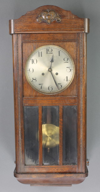 A striking wall clock with silvered dial contained in an oak case 