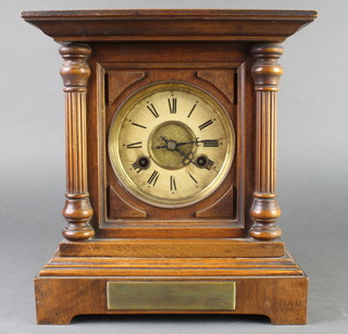 An Edwardian striking mantel clock with paper dial and Arabic numerals contained in a carved walnut case 