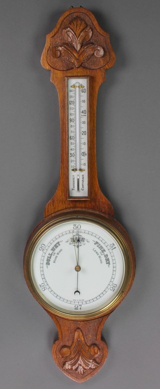 An aneroid barometer and thermometer with porcelain dial contained in a carved oak wheel case