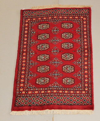 A Royal Mori red ground Bokhara style rug with 12 octagons to the centre 48" x 30" 