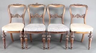 A set of 4 Victorian carved mahogany buckle back dining chairs with carved mid rails and upholstered seats raised on turned supports 