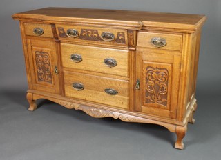 An Art Nouveau bleached oak breakfront sideboard, the centre fitted 3 long drawers flanked by 2 short drawers above a  cupboard enclosed by carved panelled doors and raised on cabriole supports 36"h x 61"w x 20"d