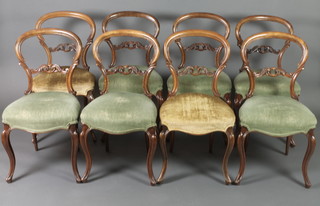 A set of 8 Victorian mahogany balloon back dining chairs with carved and pierced mid rails, the seats of serpentine outline, raised on French cabriole supports 