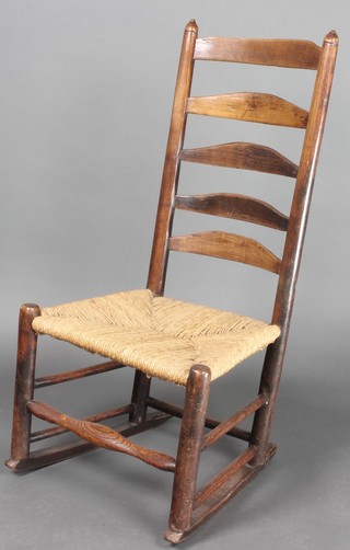 An 18th/19th Century elm ladder back rocking chair with woven rush seat 