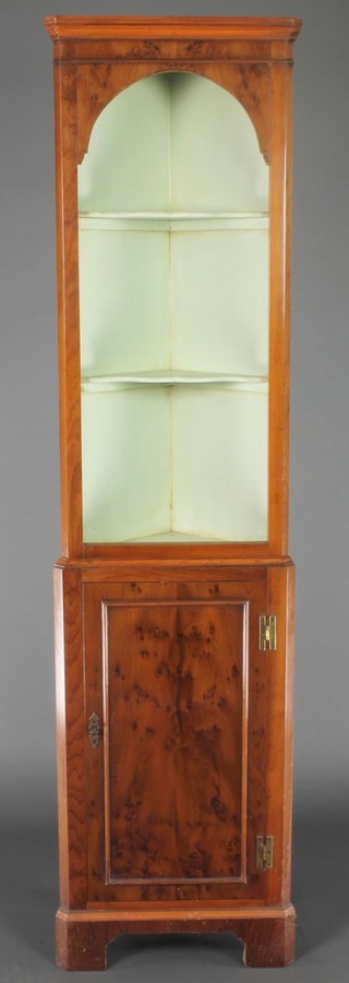 A Georgian style yew double corner cabinet, the upper section with moulded cornice fitted shelves, the base fitted shelves enclosed by a panelled door, raised on bracket feet 66 1/2"h x 17"w x 10"d 