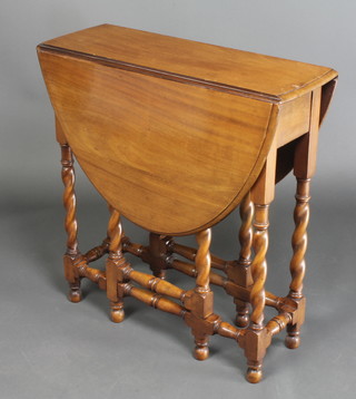 A walnut oval drop flap gateleg tea table, raised on spiral turned supports 27"h x 26 1/2"w x 9" when closed x 38" when open 