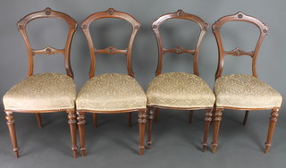 A set of 4 Victorian walnut rail back dining chairs with carved mid rails and over stuffed seats, raised on turned and fluted supports 