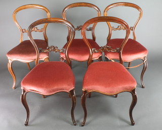 A set of 5 Victorian rosewood balloon back dining chairs with carved mid rails, the seats of serpentine outline, raised on cabriole supports