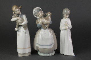 A Lladro figure of a girl holding a lamb 8 1/2", 2 Nao figures - girl in night dress 8" and a girl with lamb 8" 