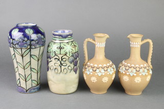 A Royal Doulton Art Nouveau waisted vase with stylised flowers 8", a ditto cylindrical vase decorated with grapes 7 1/5" and a pair of ewers with applied decoration 