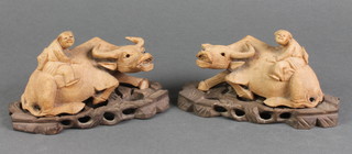 A pair of Chinese carved hardwood figures of seated buffalos with attendants, raised on hardwood stands 7" 