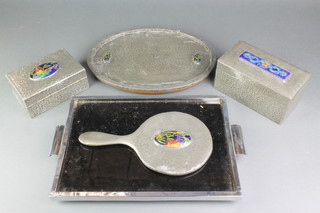 An Art Nouveau rectangular planished pewter twin section cigarette box with hinged lid inset a rectangular enamelled panel 4"h x 7 1/2"w x 4"d, a ditto trinket box inset an oval panel decorated a bridge 3"h x 6"w x 4"d, a similar hand mirror and oval tray 13" x 10" together with an Art Deco rectangular tea tray  