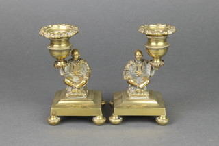 A handsome pair of 19th Century brass candlesticks in the form of seated figures, raised on square bases with detachable sconces 5" 