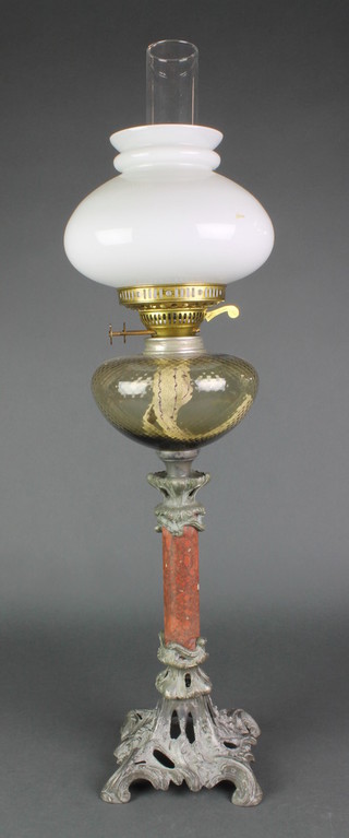 An Art Nouveau brass oil lamp raised on a pink veined column with pierced spelter base with clear glass shade and chimney