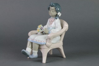 A Lladro figure of a young girl sitting in a wicker chair holding a bouquet. 5699 6 1/2" 