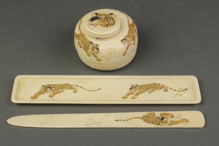 A Japanese carved and stained circular ivory box, tray and paper knife decorated with tigers 