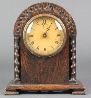 A 1930's bedroom timepiece with paper dial and Roman numerals contained in a carved oak arch shaped case 