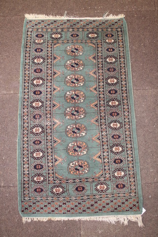 A green ground Bokhara slip rug with 8 octagons to the centre, 24" x 25" slight wear