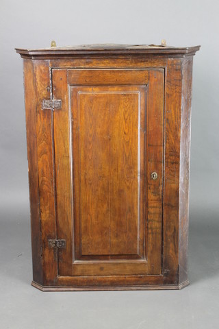 A 19th Century elm and oak hanging corner cabinet with moulded cornice, the shelved interior enclosed by a panelled door, 42"h x 30"w x 17"d 