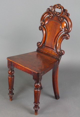 A Victorian oak hall chair with shield shaped back and solid seat, raised on turned supports 