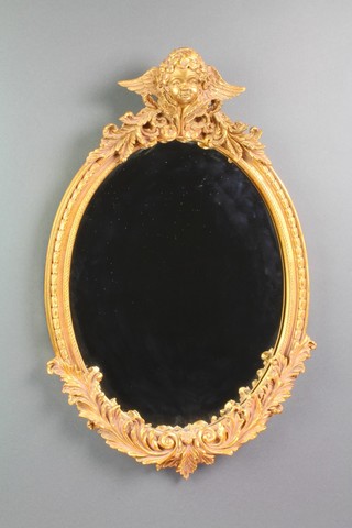 An oval plate wall mirror contained in a decorative gilt frame surmounted by a figure of a cherub 20 1/2h x 13"w 