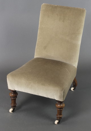A Victorian nursing chair upholstered in light green material, raised on turned supports 
