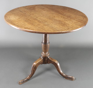 An 18th Century oak snap top tea table, raised on a turned column and tripod base 29 1/2"h x 33"diam. 