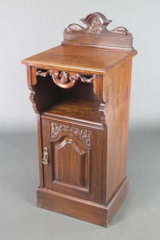 A Victorian carved walnut pot cupboard with raised back above a recess, the base fitted a drawer and raised on a platform base 38"h x 16"w x 15 1/2"d 