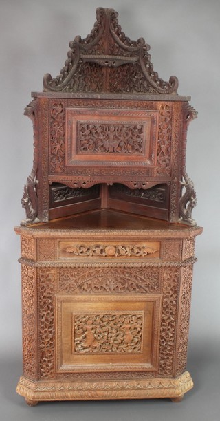 A 19th Century carved Burmese hardwood corner cupboard, the upper section with pierced back fitted a cupboard above recess, the base fitted a cupboard enclosed by a panelled door 75"h x 35"w x 20"d 