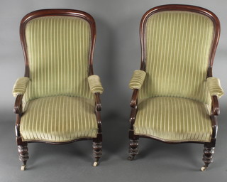 A pair of  Victorian mahogany show frame open arm chairs upholstered in green material, raised on turned supports 
