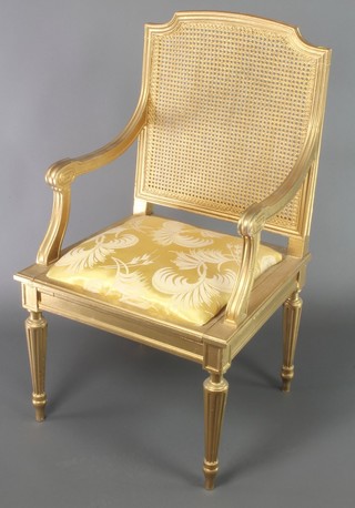 A gilt painted commode chair with woven cane back, raised on turned and fluted supports 