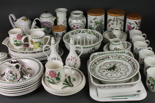 A Portmeirion Botanic Garden tea and dinner service, comprising 4 lidded storage jars, watering can, coffee pot and lid, 2 casseroles, 6 oval plates, oval serving plate, 6 mugs, 2 oil bottles, a toast rack, lidded pot, preserve pot, 2 small dishes, pair of servers, jug, 7 plates, 6 soup bowls, 4 dessert bowls, small vase, wall clock, spill vase, salad bowl, sauce jug and stand, jug, 3 mugs, cake stand, tray and 6 place mats 