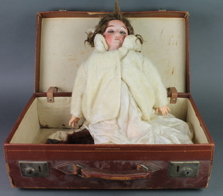 A German porcelain headed doll with opening and shutting eyes, open mouth and teeth, the head incised Germany R11A contained in a leather suitcase 