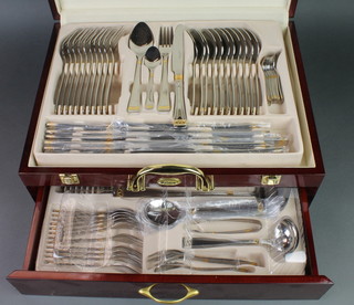 A mahogany case containing a canteen of Prima stainless steel gilt decorated cutlery for 10 
