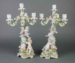 A pair of late 19th Century German porcelain 4 light candelabra decorated with cherubs and flowers on Rococo bases 14"  