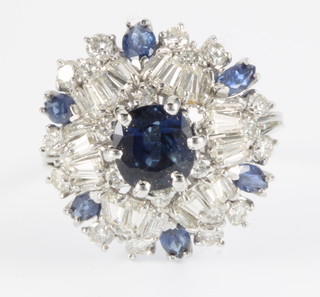 An 18ct white gold sapphire and diamond cocktail ring, set with oval sapphires and brilliant cut and tapered baguette cut diamonds, size M