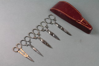 A set of 4 bright cut scissors contained in a Moroccan red leather case together with a pair of 19th Century gold scissors 