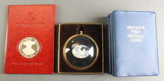 A Birmingham Mint, Alfred Russel Wallace commemorative crown, a framed cameo plaque and 12 Britain's first decimal coin sets 